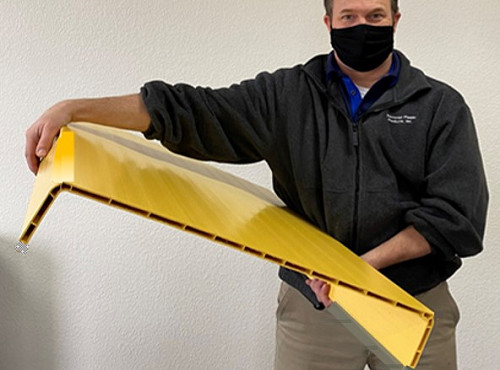 Employee holding a sample of a large plastic extruded profile